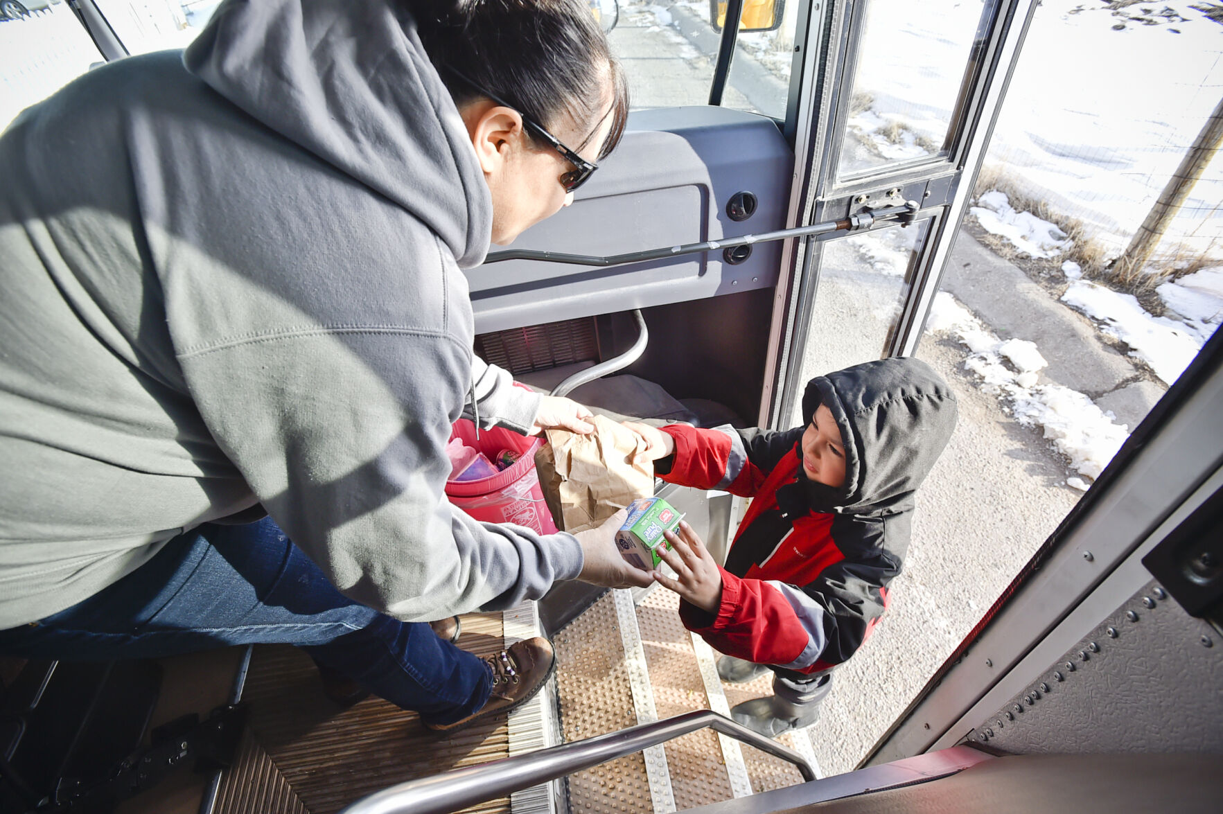 Nicklo Crossguns hands a young boy a sack breakfast